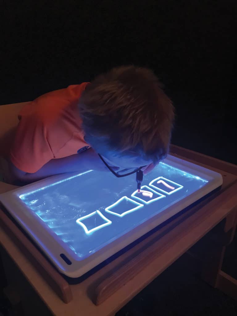 Young boy practicing writing skills with a light board