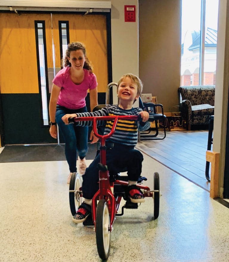 Young smiling boy riding a bike in physical therapy