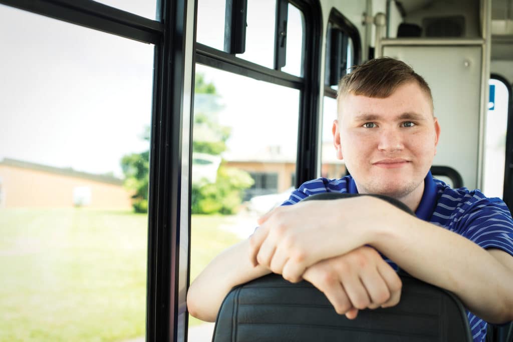 Man in his 20s posing and smiling on a bus